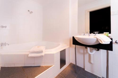 a white bathroom with a sink and a tub at Athelstane House in Queenscliff