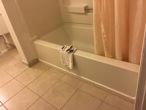 y baño con bañera y suelo de baldosa. en National 9 Inn Sand Canyon, en Cortez