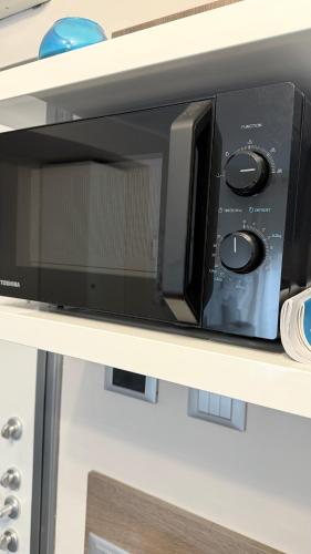 a microwave oven sitting on top of a shelf at Bloom Apartment in Pero