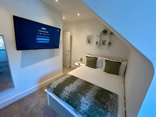 a bedroom with a bed with a tv on the wall at Gogmore Lane in Chertsey