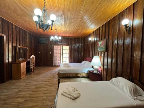 Coronel BogadoにあるHotel Estancia Itapúaのベッドが2つとシャンデリアがあるホテルの部屋