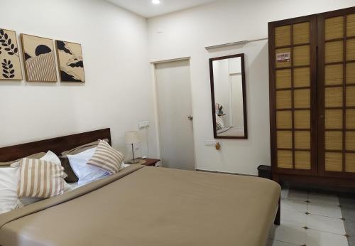 a bedroom with a large bed and a mirror at Casa Mel in Puducherry