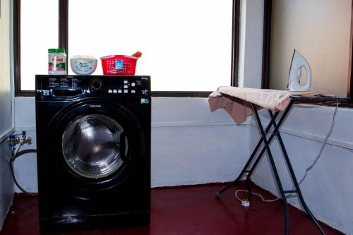 a black washing machine in a room with a table at KAREN Comfort 3BR Holiday Home Nandi Rd off Miotoni in Nairobi