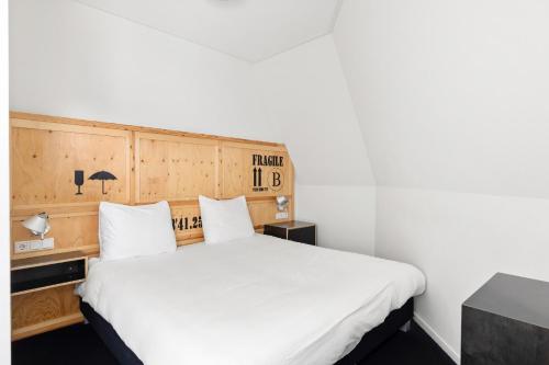a bedroom with a large bed with white sheets at B's Strandappartementen in Domburg