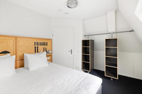 a bedroom with a large white bed and shelves at B's Strandappartementen in Domburg