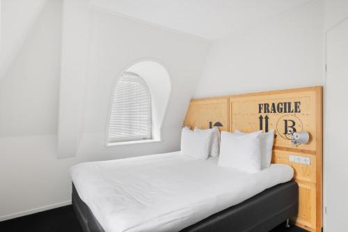 a bedroom with a white bed with a wooden headboard at B's Strandappartementen in Domburg