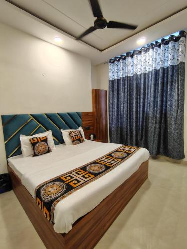 Schlafzimmer mit einem großen Bett und blauen Vorhängen in der Unterkunft Aastha View in Amritsar