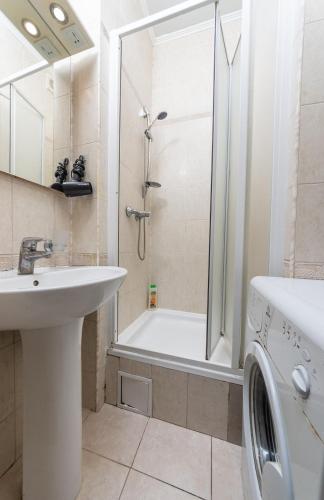 a bathroom with a shower and a sink and a washing machine at Простора квартира біля Майдану Незалежності in Kyiv