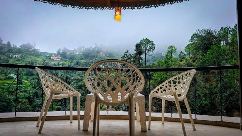 two chairs sitting on a balcony with a view at Neelkanth Cozy Stays Mukteshwar in Mukteswar