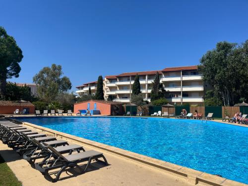 a large swimming pool with lounge chairs in front of a building at Appartement T2 proche de la plage avec parking gratuit in Canet-en-Roussillon