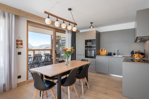 una cucina e una sala da pranzo con tavolo e sedie in legno di Apartment Vallejo Alpe D'Huez - by EMERALD STAY a LʼHuez