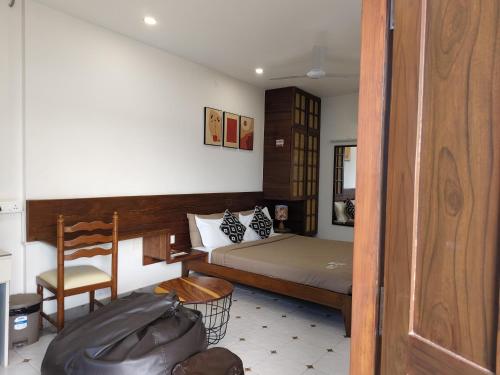 a small bedroom with a bed and a chair at Casa Mel in Puducherry
