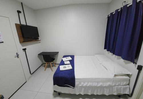a bedroom with a bed and a tv in it at Hotel Moriah in Umuarama