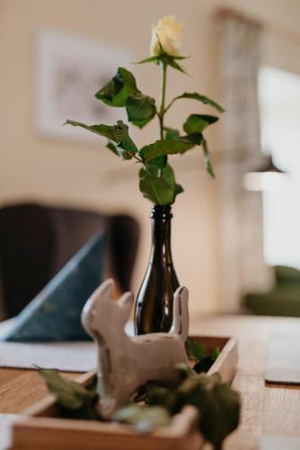 a vase with a rose in it sitting on a table at Ferienwohnungen Hotel Garni Dörflerwirt in Aflenz Kurort