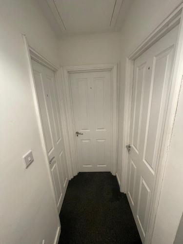 an empty hallway with white doors and black carpet at Modern 4 Bed Home, Free Parking in Hartlepool town in Hartlepool