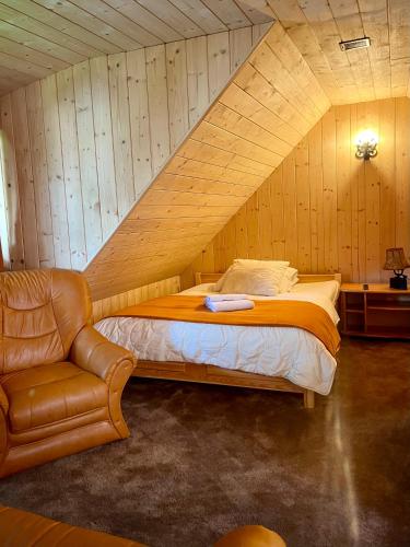 a bedroom with a bed and a chair in a attic at Willa Pod Orłem Jacuzzi Sauna in Kościelisko