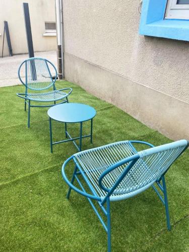 two blue chairs and a table on the grass at Chambre privée à 50 m de la plage- Parking privé, salle de bain et cuisine commune in Le Portel