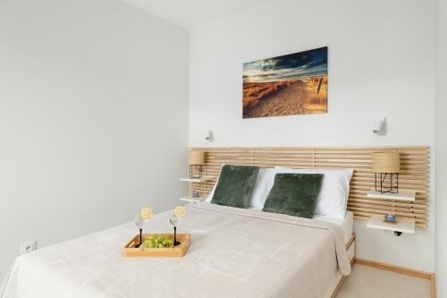 una camera da letto con un letto bianco con testiera in legno di Eleganckie Apartamenty Blisko Plaży w Niechorzu z Klimatyzacją w Salonie i Parkingiem by Noclegi Renters a Niechorze