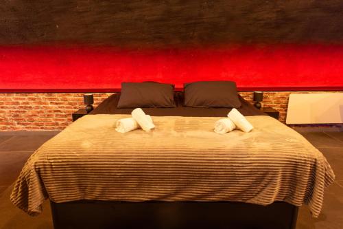 une chambre avec un grand lit avec un mur rouge dans l'établissement L'escapade Vosgienne, à Remiremont