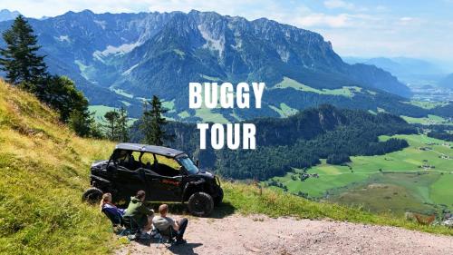 a group of people sitting on a hill next to a jeep at Appartementhaus Ederegger in Ebbs