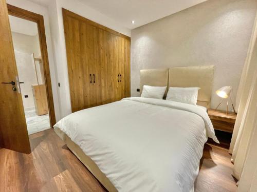 Schlafzimmer mit einem großen weißen Bett und Holzboden in der Unterkunft D1115 Studio au Cœur de Casablanca Proximité et Confort1 in Casablanca