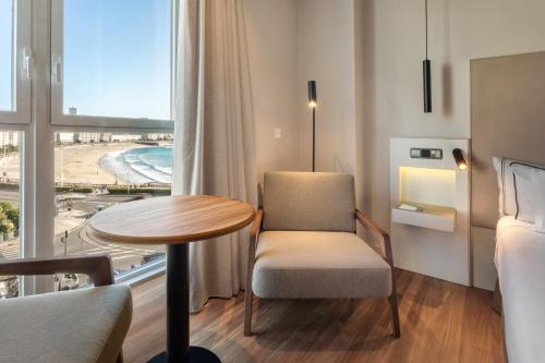 a room with a table and a chair and a window at Melia Maria Pita in A Coruña