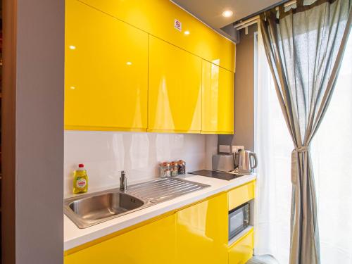 a kitchen with yellow cabinets and a sink at City Center Studio Apartments By AVO Apartments Sheffield in Sheffield