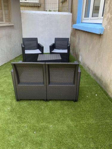 two chairs and a table on a patio with grass at Chambre privée à 50 m de la plage- Parking privé, salle de bain et cuisine commune in Le Portel