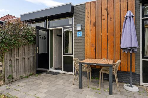 a table and chairs and an umbrella next to a building at RCN Vakantiepark Toppershoedje in Ouddorp
