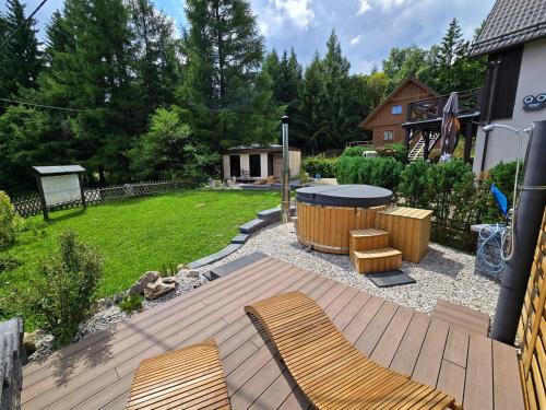 a backyard with a wooden deck with chairs and a table at Penzion Studánka, Klíny in Klíny