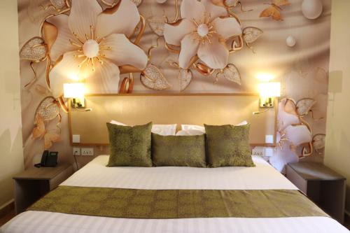 - une chambre avec un lit orné de fleurs sur le mur dans l'établissement Lake Naivasha Resort, à Naivasha