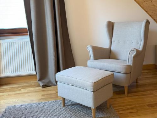 a chair and stool in a room with a window at Bartoszy Zakątek in Bartoszylas