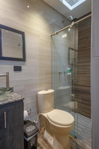 a bathroom with a toilet and a glass shower at Hostal Machu Picchu Medellín in Medellín