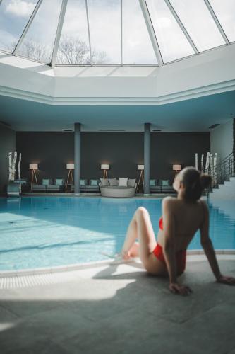 a woman sitting in front of a swimming pool at Hotel Montis - Schönblick in Brunico
