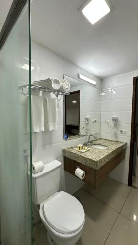 a white bathroom with a toilet and a sink at Tambaú Beira-Mar in João Pessoa