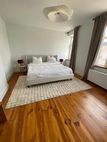 a bedroom with a white bed and a wooden floor at Cièlo in Tongeren