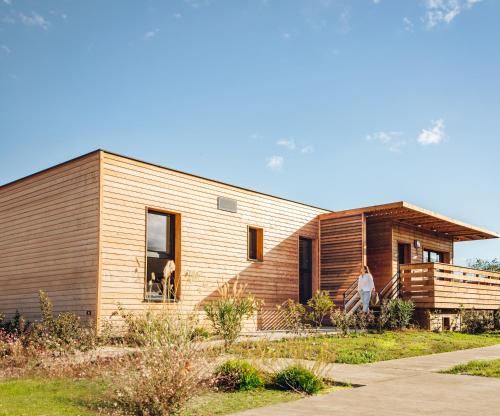 une maison en bois avec deux personnes debout à l'extérieur dans l'établissement Résidence Pierre & Vacances Premium Domaine du Golfe du Lion, à Saint-Cyprien