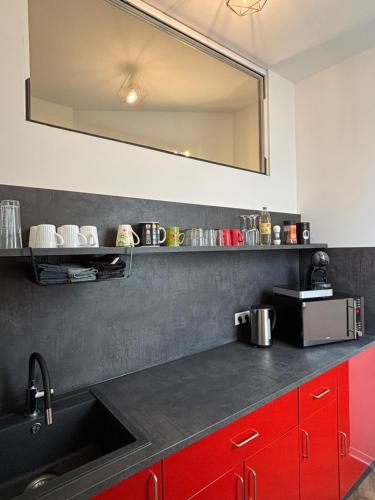a kitchen with a sink and red cabinets and a mirror at Top Appartement in Bremerhaven