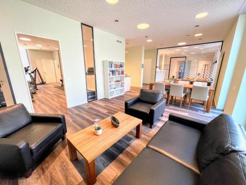 a living room with black leather furniture and a table at ARISER - Luzern Kriens Business Suites in Luzern