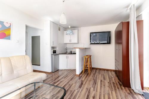 a living room with a white couch and a kitchen at Chmielna str Super Central Apartment in Warsaw