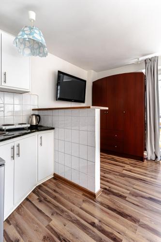 a kitchen with white cabinets and a tv on the wall at Chmielna str Super Central Apartment in Warsaw