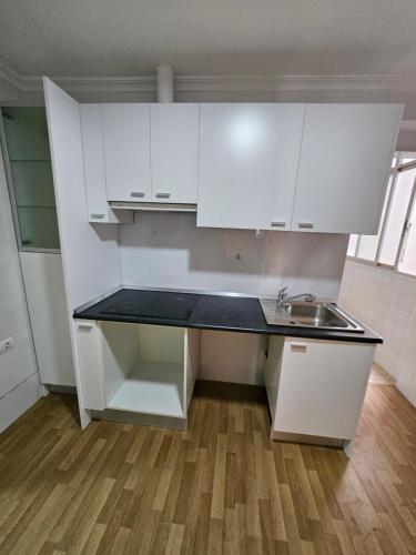 a small kitchen with white cabinets and a sink at Apto en San Antonio a un paso de la playa in Cullera