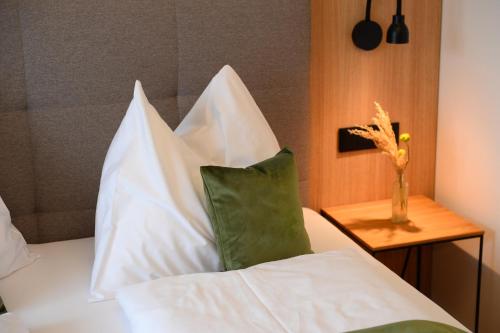 a bed with white pillows and a green pillow at Landgasthof Sagenhaft in Klagenfurt