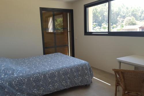 a bedroom with a bed and a table and a window at Maison des Vignes Swimming pool and charm in Lauris in Lauris