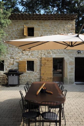 a wooden table with chairs and an umbrella at Maison des Vignes Swimming pool and charm in Lauris in Lauris