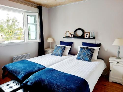 Saint-Germain-de lʼHomelにあるLes Chambres d'Hôtes du Parcの青い枕が付いた大きなベッドのある寝室