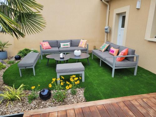 d'une terrasse avec deux canapés et une table sur gazon. dans l'établissement Baune, à La Bazoge