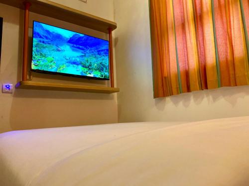 a bedroom with a bed and a television in a window at NiHOTEL Cibaduyut Bandung in Bandung
