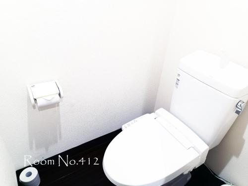 a bathroom with a white toilet and a toilet paper dispenser at Ace Inn Asakusa in Tokyo