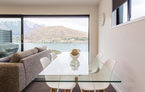 a dining room with a glass table and white chairs at Highland Views in Queenstown